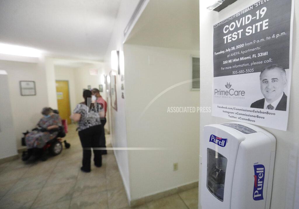 A sign informing residents of COVID-19 testing is shown, Tuesday, July 28, 2020, at the AHEPA Apartments in Miami. Miami-Dade County Commissioner Esteban "Steve" Bovo and Prime Care Family Medical Centers opened the free testing site to test the residents of the senior apartments. (AP Photo/Wilfredo Lee)