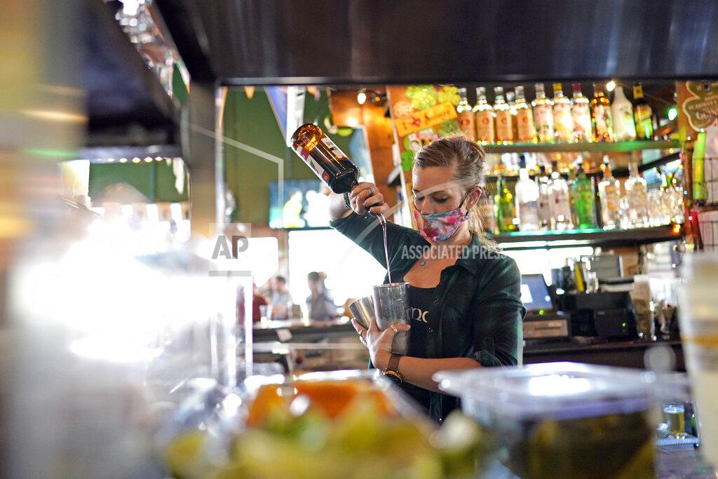 David J. Phillip Bartender Alyssa Dooley makes a cocktail at Mo's Irish Pub, Tuesday, March 2, 2021, in Houston. Texas Gov. Greg Abbott announced Tuesday that he is lifting business capacity limits and the state's mask mandate starting next week. (AP Photo/David J. Phillip)