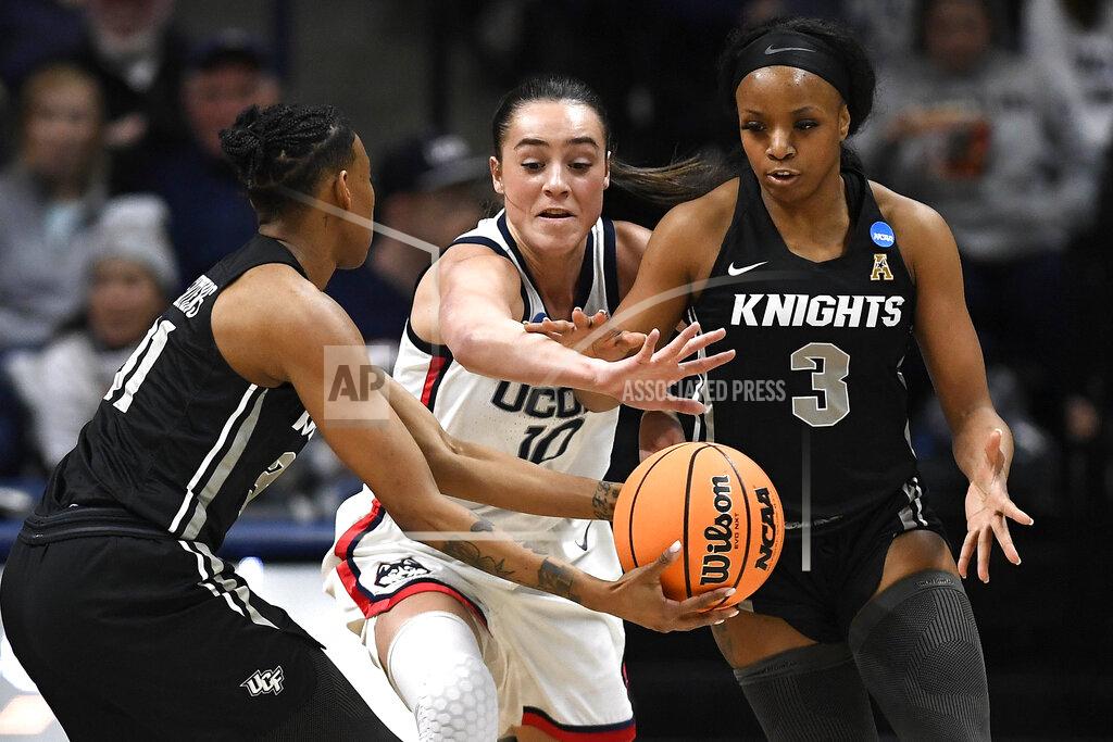 Jessica Hill Central Florida's Shania Meertens passes to Central Florida's Diamond Battles, right, under pressure from Connecticut's Nika Mühl, center, during the first half of a second-round college basketball game in the NCAA tournament, Monday, March 21, 2022, in Storrs, Conn. (AP Photo/Jessica Hill)