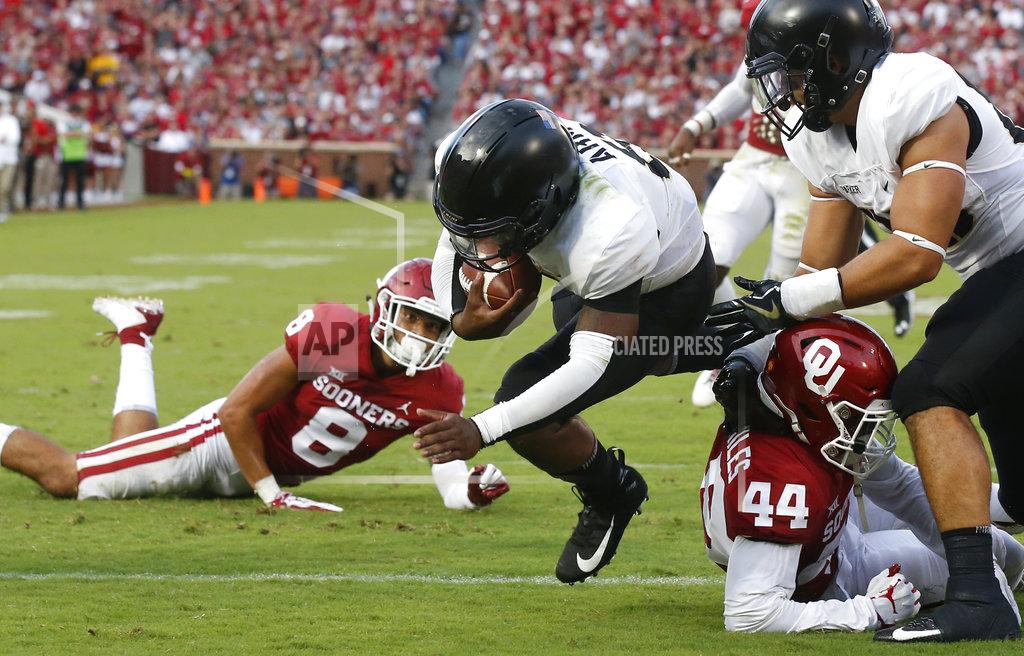 Sue Ogrocki FILE - In this Saturday, Sept. 22, 2018, file photo, Army quarterback Kelvin Hopkins Jr. (8) scores between Oklahoma safety Kahlil Haughton (8) and defensive back Brendan Radley-Hiles (44) in the first half of an NCAA college football game in Norman, Okla. A year ago quarterback Hopkin knew he wasn’t going to see much playing time under center for Army because starter Ahmad Bradshaw was having a stellar senior season for the Black Knights. Now, Hopkins is the lead man and has the demeanor he needs.(AP Photo/Sue Ogrocki)