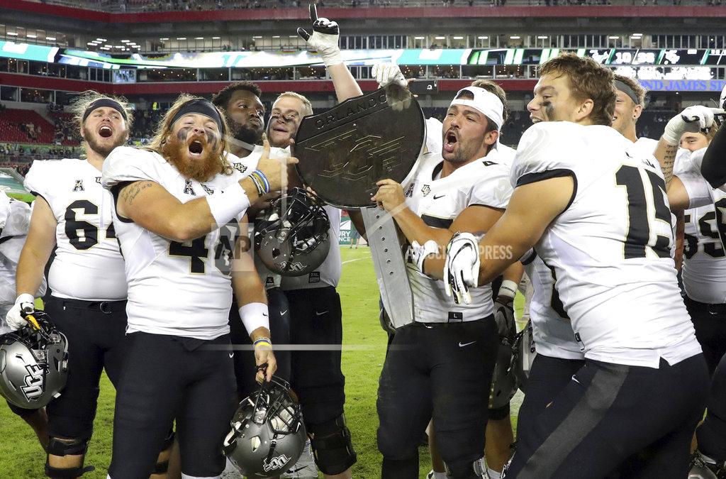 Mike Carlson Central Florida celebrates with the War on I-4 trophy after defeating South Florida in an NCAA college football game Friday, Nov. 23, 2018, in Tampa, Fla. (AP Photo/Mike Carlson)