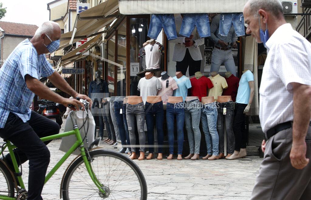 Boris Grdanoski Men pass a clothing shop in the Old Bazaar in Skopje, North Macedonia on Thursday, July 16, 2020. The pro-Western SDSM party in North Macedonia is poised to try to form a coalition government following a narrow election victory. (AP Photo/Boris Grdanoski)