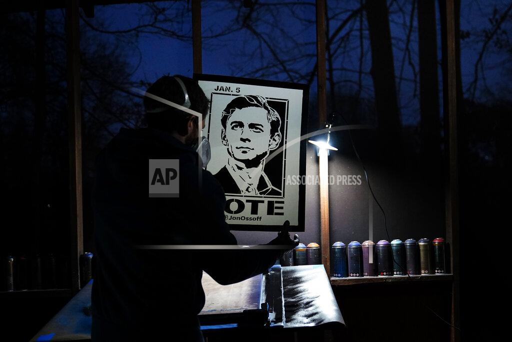Brynn Anderson Artist Brandon Litman holds up a U.S. Senator-elect Jon Ossoff, D-Ga., campaign poster after spray painting it after Georgia's Senate runoff race on Saturday, Jan. 9, 2021, in Atlanta. (AP Photo/Brynn Anderson)