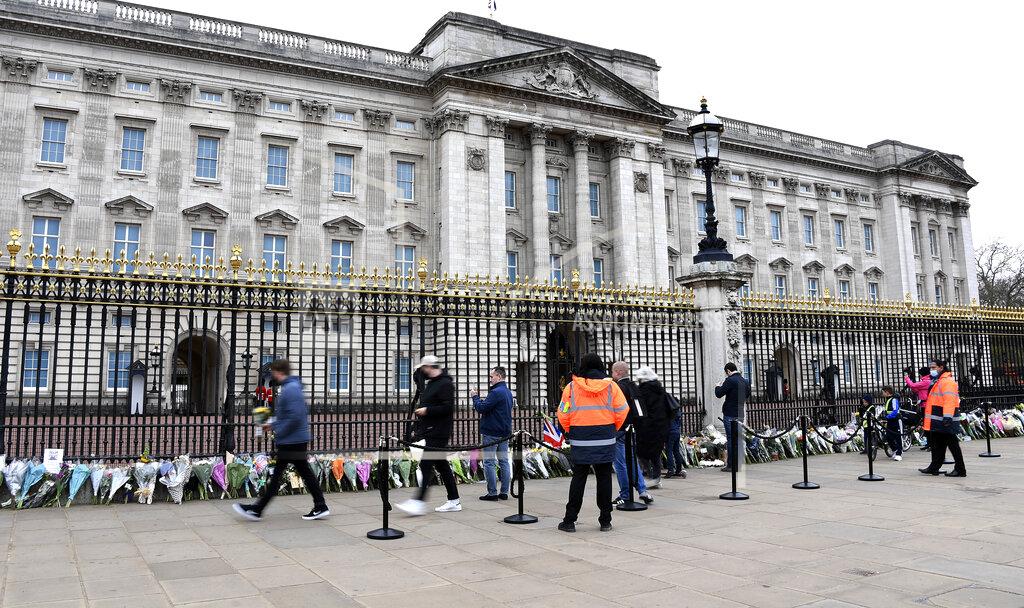 People leave flowers and take photos outside the gates of Buckingham Palace in London, a day after the death of Britain's Prince Philip, Saturday, April 10, 2021. Britain's Prince Philip, the irascible and tough-minded husband of Queen Elizabeth II who spent more than seven decades supporting his wife in a role that mostly defined his life, died on Friday. (AP Photo/Alberto Pezzali)
