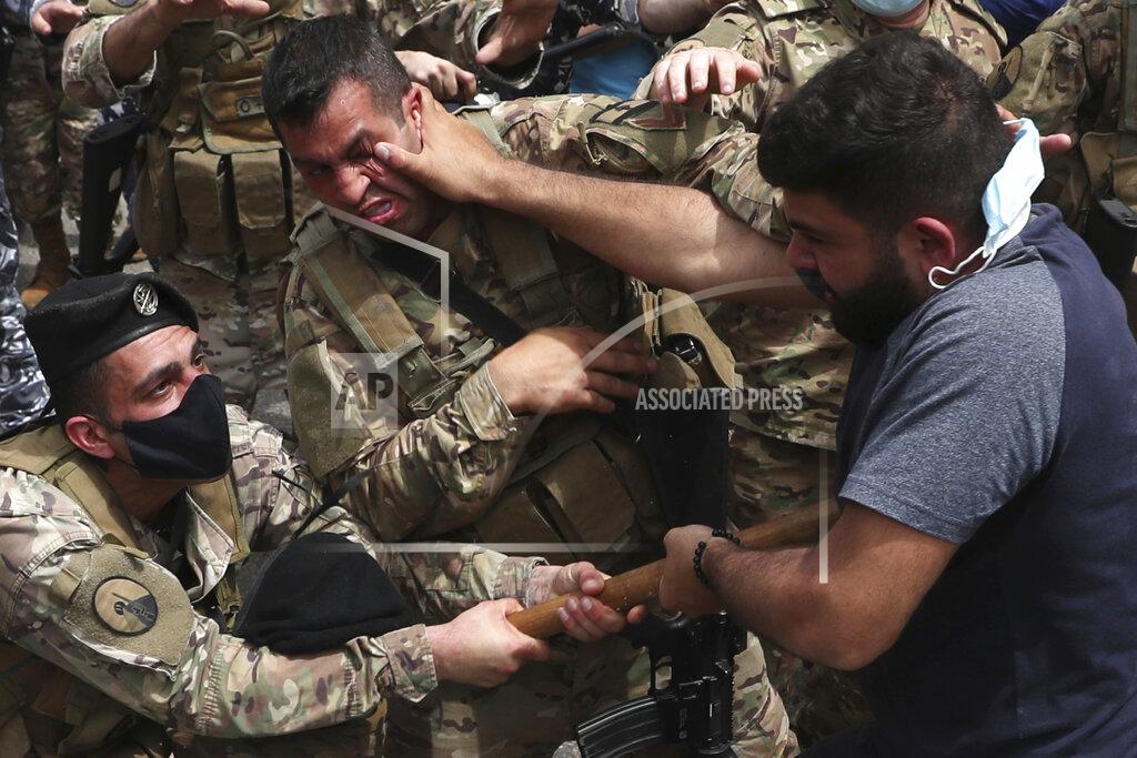 Bilal Hussein FILE - In this April 19, 2021 file photo, opponents of Judge Ghada Aoun scuffle with army soldiers during a sit-in outside the Justice Palace in Beirut, Lebanon. A public feud in recent weeks among prosecutors has starkly demonstrated how Lebanon's system of sectarian factions is paralyzing Lebanon's judicial system and snarling attempts to root out corruption. Aoun, a prominent prosecutor says she is trying to go after rampant corruption but her critics say she is only targeting enemies of her ally, the president. (AP Photo/Bilal Hussein, File)