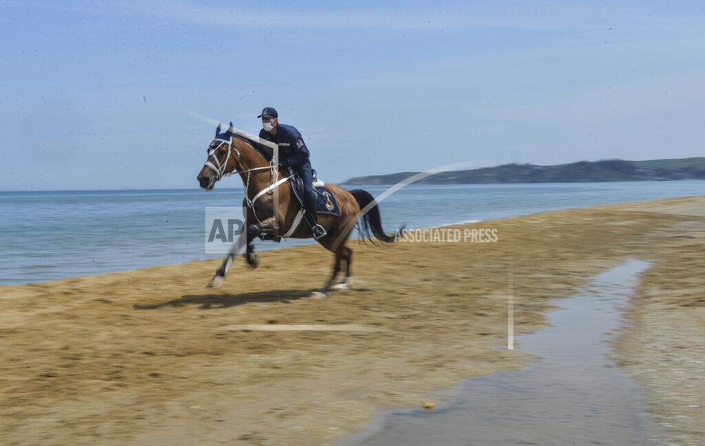 Ibrahim Mase A member of the Equestrian Gendarmerie Unit, which normally serve to protect the Topkapı Palace, wearing face masks for protection against the coronavirus, as they patrol the beaches in Sariyer outside Istanbul, Saturday, May 2, 2020. The equestrian unit is used to patrol the beach area to enforce the curfew measures, restricting people from walking around or swimming. (Ibrahim Mase/DHA via AP)