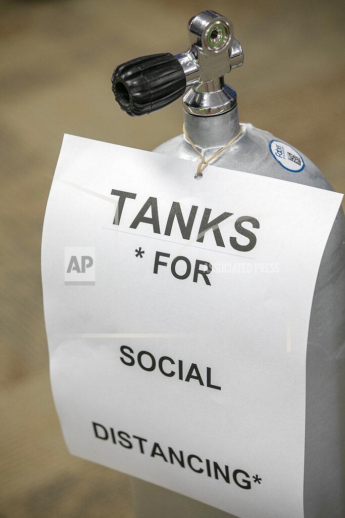 A social distancing sign attached to an oxygen tank at New England Dive, in Wallingford, Conn., Monday, May 18, 2020. The store reopens Wednesday. (Dave Zajac/Record-Journal via AP)