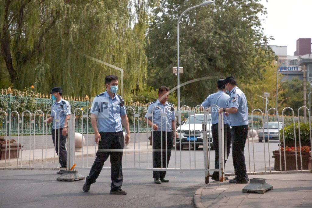 Mark Schiefelbein Police officers pull a barricade across a road leading to the a residential neighborhood near the Xinfadi wholesale food market district in Beijing, Saturday, June 13, 2020. Beijing closed the city's largest wholesale food market Saturday after the discovery of seven cases of the new coronavirus in the previous two days. (AP Photo/Mark Schiefelbein)