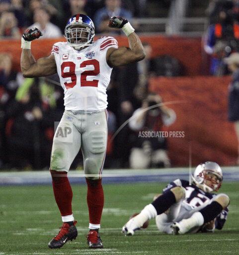 FILE - In this Feb. 3, 2008 file photo, New York Giants defensive end Michael Strahan (92) reacts after sacking New England Patriots quarterback Tom Brady (12) in the third quarter of the Super Bowl XLII football game at University of Phoenix Stadium in Glendale, Ariz. Strahan is looking forward to seeing his No. 92 jersey retired by the Giants, and wondering why it took so long. The never-shy Strahan on Wednesday, Nov. 24, 2021 took a swipe at the team's ownership for lateness of his jersey retirement, nipped at fans of the rival Philadelphia Eagles and added he is as frustrated as any Giants fan by the team struggles over the past decade. (AP Photo/David Duprey, file)