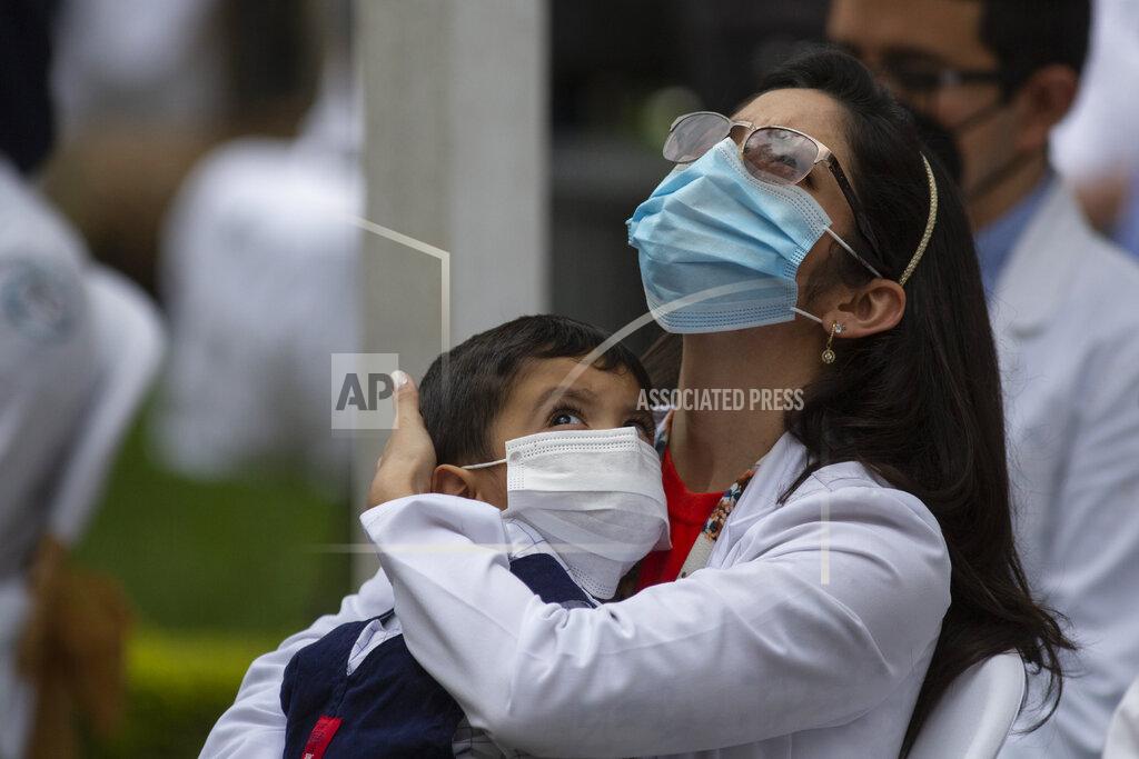 Moises Castillo A health worker at the San Juan de Dios hospital holds a child during a minute of silence in memory of her colleagues who have fallen victim to COVID-19 in Guatemala City, Friday, Oct. 9, 2020. (AP Photo/Moises Castillo)