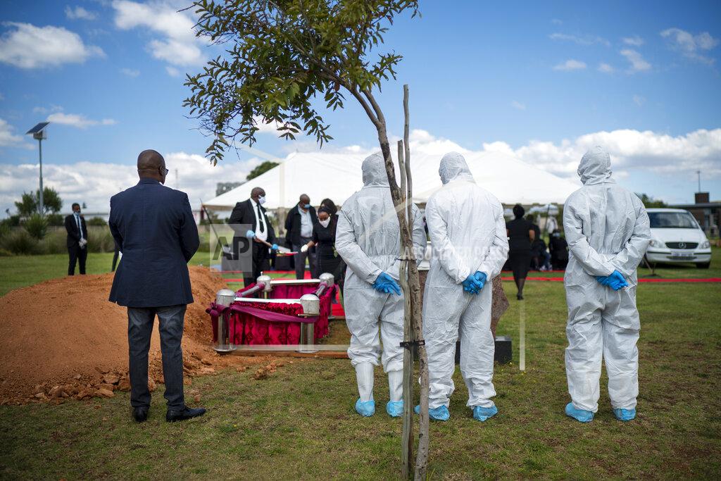 Jerome Delay Pallbearers wearing full PPE stand behind the grave of Benedict Somi Vilakasi during his funeral ceremony at the Nasrec Memorial Park outside Johannesburg Thursday, April 16, 2020. Vilakasi, a Soweto coffee shop manager, died of Covid-19 infection in a Johannesburg hospital Sunday April 12 2020. South Africa is under a strict five-week lockdown in a effort to fight the Coronavirus pandemic.(AP Photo/Jerome Delay)
