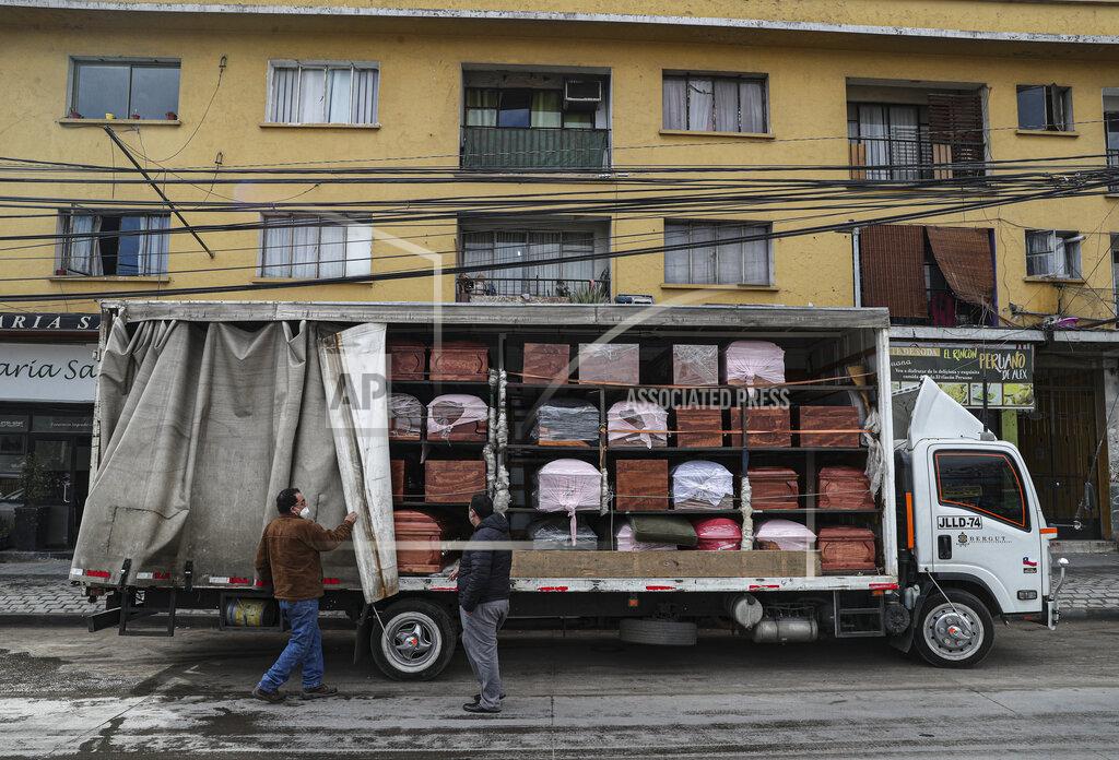 Esteban Felix Bergut Funeral Services employees deliver coffins to a funeral store in Santiago, Chile, Friday, June 19, 2020. Coffin production has increased 120%, according to owner Nicolas Bergerie. A basic coffin penned the COVID model was designed to cope with the increase of deaths during the new coronavirus pandemic. (AP Photo/Esteban Felix)