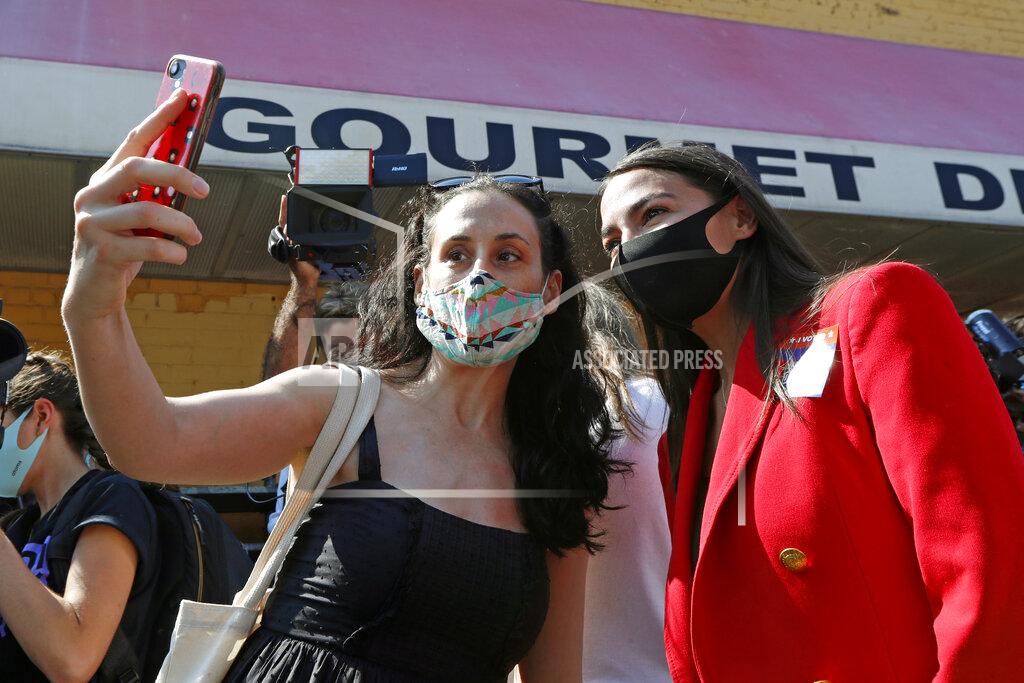 Kathy Willens U.S. Rep. Alexandria Ocasio-Cortez, D, New York, right, poses for a photo with a supporter as she greeted voters in Astoria, Queens, Tuesday, June 23, 2020, on primary election day in New York. The first-term congresswoman is facing several challengers in her bid to hold onto her seat. (AP Photo/Kathy Willens)