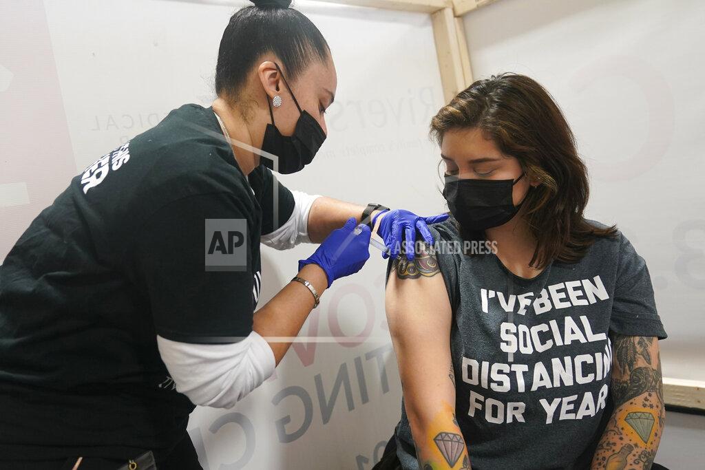 Seth Wenig Denise Padilla, right, an instructor at the culinary school at Eva's Village, is vaccinated in Secacus, N.J., Sunday, Feb. 28, 2021. In an effort to vaccinate undeserved populations, Riverside Medical Group partnered with Eva's Village, an anti-poverty non-profit, to help vaccinate over 80 of their clients and staff members. (AP Photo/Seth Wenig)