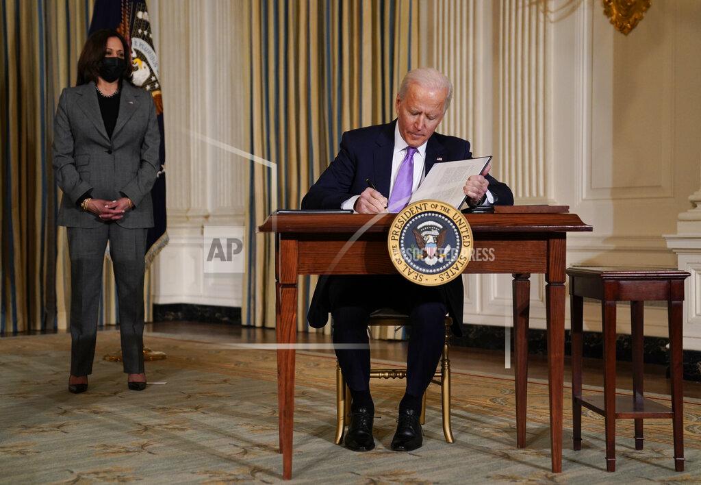 Evan Vucci President Joe Biden signs executive orders in the State Dining Room of the White House, Tuesday, Jan. 26, 2021, in Washington. Vice President Kamala Harris listens at left. (AP Photo/Evan Vucci)