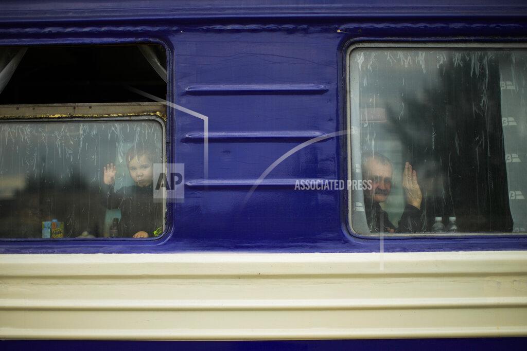 Francisco Seco A child and a man, fleeing from heavy shelling, wave to the photographer before departing in an evacuation train at Pokrovsk train station, in Pokrovsk, eastern Ukraine, Sunday, May 22, 2022. Civilians fleeing areas near the eastern front in the war in Ukraine Sunday described scenes of devastation as their towns and villages came under sustained attack from Russian forces. (AP Photo/Francisco Seco)