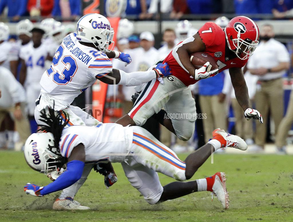 John Raoux Georgia running back D'Andre Swift (7) runs for yardage over Florida defensive back Chauncey Gardner-Johnson (23) and defensive back Shawn Davis, lower left, during the second half of an NCAA college football game Saturday, Oct. 27, 2018, in Jacksonville, Fla. (AP Photo/John Raoux)