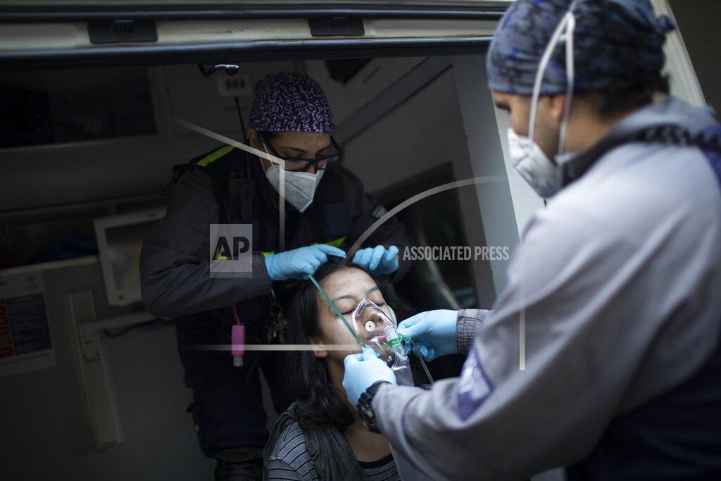 Ariana Cubillos Wearing masks as a precaution against the new coronavirus, Angels of the Road volunteer paramedics Rodolfo Alvarado, right, and Zully Rodiz, place an oxygen mask on a woman who was in a residential building when a car burst into flames in the parking lot, in Caracas, Venezuela, Monday, Feb. 8, 2021. Despite receiving no paychecks, the roughly 40 volunteer paramedics are ready at a moment's notice to jump onto motorcycles and fire up their single ambulance and race into the streets to attend an emergency. (AP Photo/Ariana Cubillos)
