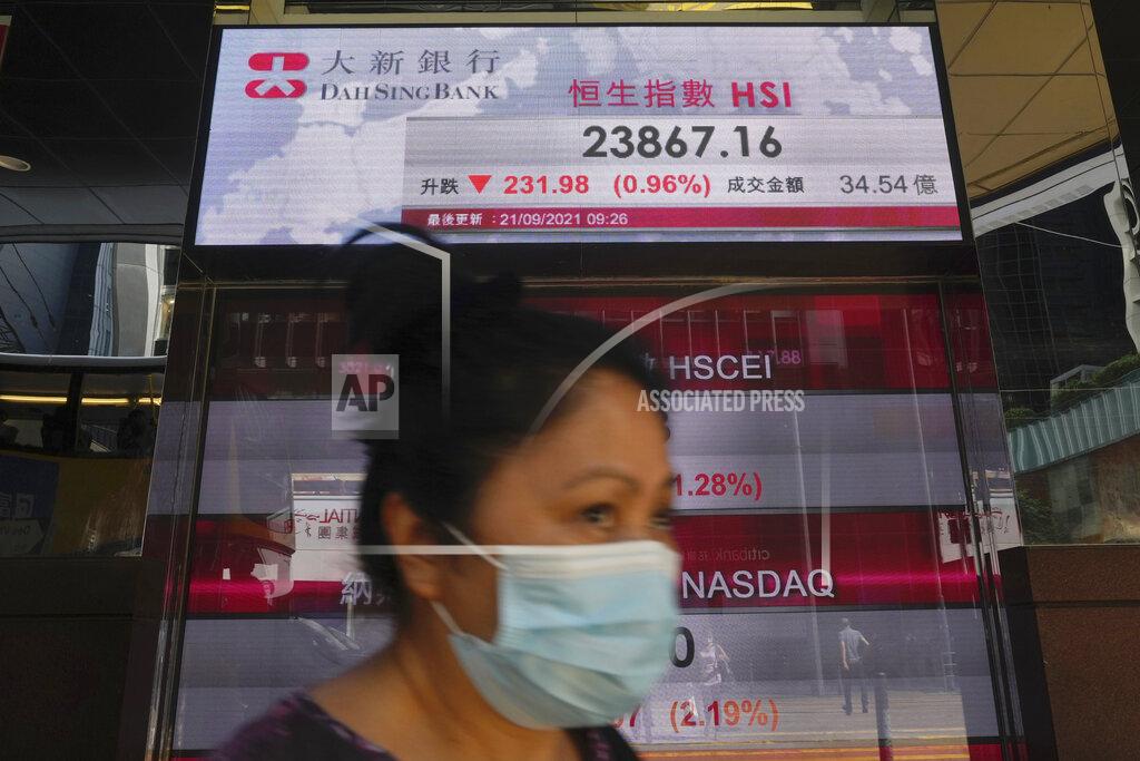 Vincent Yu A woman walks past a bank's electronic board showing the Hong Kong share index at Hong Kong Stock Exchange in Hong Kong Tuesday, Sept. 21, 2021. Asian shares declined Tuesday, with Tokyo down 2% as worries about heavily indebted Chinese real estate developers weighed on sentiment. (AP Photo/Vincent Yu)
