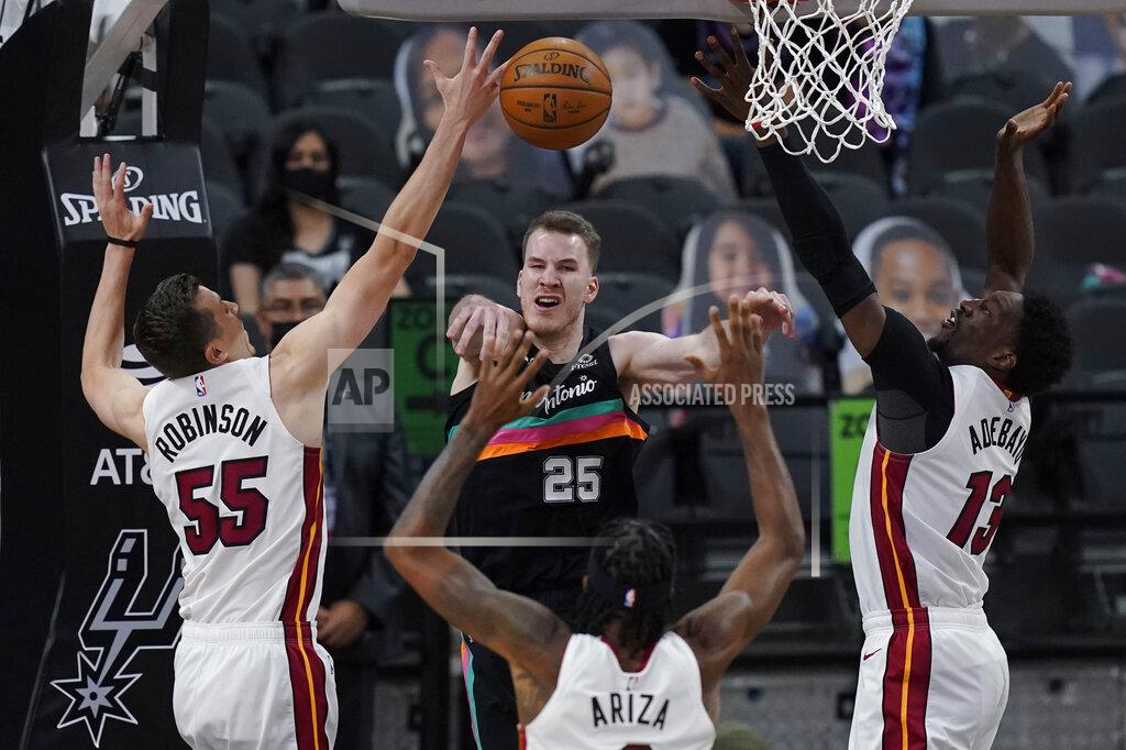 Eric Gay San Antonio Spurs center Jakob Poeltl (25) passes the ball as he is pressured by Miami Heat defenders Duncan Robinson (55), Trevor Ariza (8) and Bam Adebayo (13) during the second half of an NBA basketball game in San Antonio, Wednesday, April 21, 2021. (AP Photo/Eric Gay)