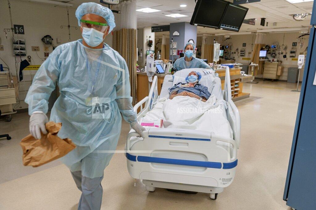 J. Kiely Jr./Lightchaser Photography CORRECTS LAST NAME TO VLASSAKOV - In this July 2020, photo released by Brigham and Women's Hospital, members of the transplant anesthesiology team, Drs. Kamen V. Vlassakov front, and Lindsay Wahl lead Carmen Blandin Tarleton to the operating room for her second face transplant at Brigham and Women's Hospital in Boston. Tarleton, who had her first face transplant in 2013, became the first American and only the second person globally to undergo a second face transplant procedure after her first transplant failed. (J. Kiely Jr./Lightchaser Photography/Brigham and Women's Hospital, via AP).