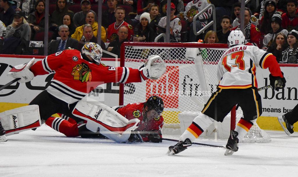 Matt Marton Calgary Flames left wing Johnny Gaudreau (13) scores a goal past Chicago Blackhawks goaltender Collin Delia, left, and center Dylan Strome (17) during the first period of an NHL hockey game on Monday Jan. 7, 2019, in Chicago. (AP Photo/Matt Marton)