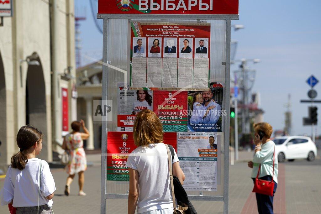 Sergei Grits People look at a billboard on the street with portraits of presidential candidates with the Belarus President Alexander Lukashenko's face covered with a white sticky tape ahead of Sunday's election in Minsk, Belarus, Tuesday, Aug. 4, 2020. Belarus's authoritarian leader is vowing to maintain a close alliance with Russia despite the latest tensions as he seeks a sixth term in office amid a surge of opposition protests. President Alexander Lukashenko's comments in a state-of-the-nation address ahead of Sunday's election contrast with his diatribes against Russia last week. (AP Photo/Sergei Grits)