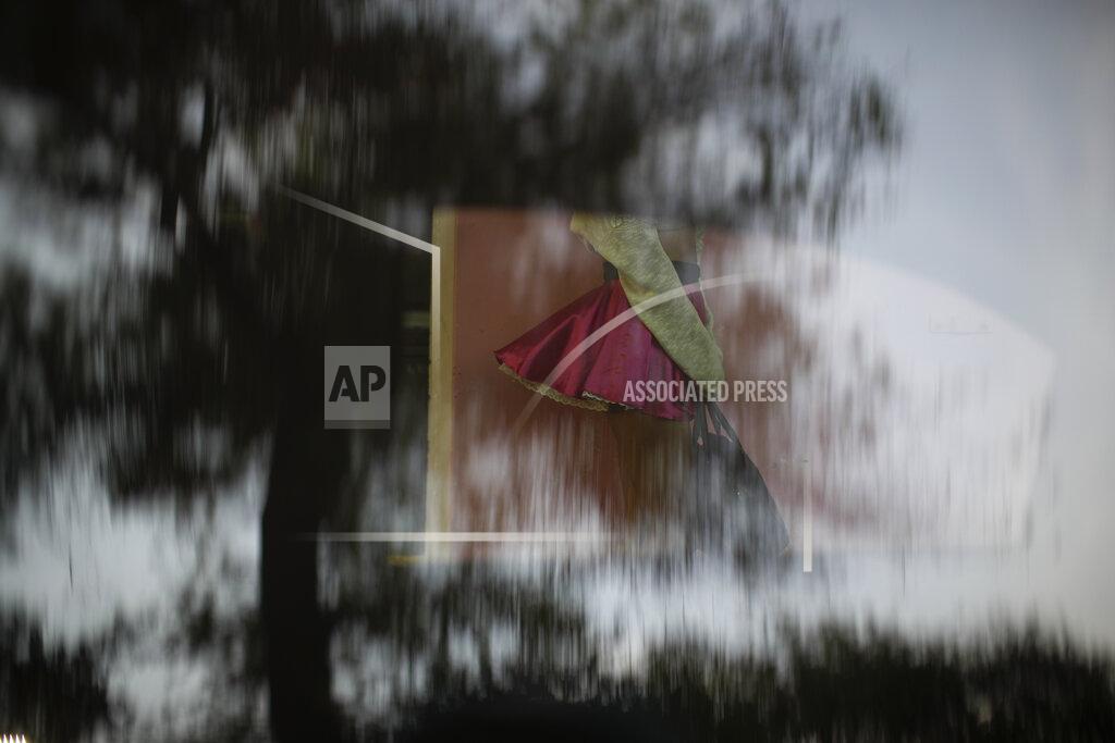 Rebecca Blackwell Sex worker Geraldine's skirt blows up in the breeze as she is seen through the reflective window of a parked car while waiting for clients near the Revolution subway station, in Mexico City, Thursday, March 25, 2021. Thousands of new sex workers have pushed onto the streets as the coronavirus pandemic forced the closure of restaurants and shops. (AP Photo/Rebecca Blackwell)
