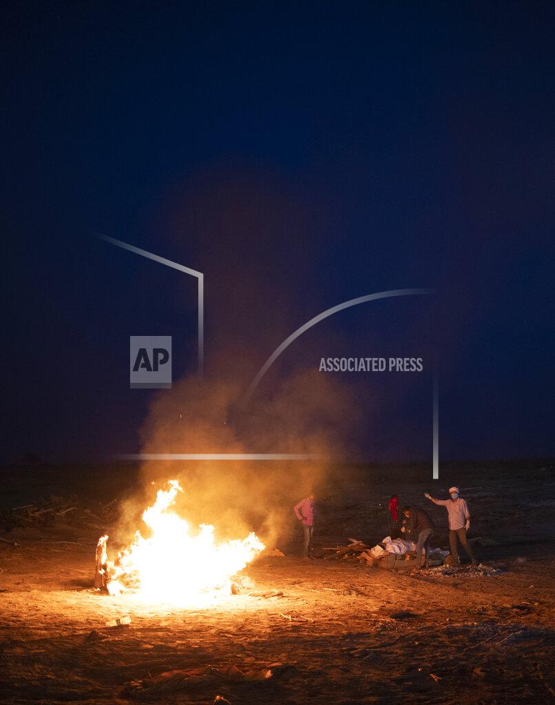 Rajesh Kumar Singh Relatives stand near the funeral pyre of their loved one who died due to COVID-19 at a cremation ground in Prayagraj, India, Saturday, May 8, 2021. (AP Photo/Rajesh Kumar Singh)