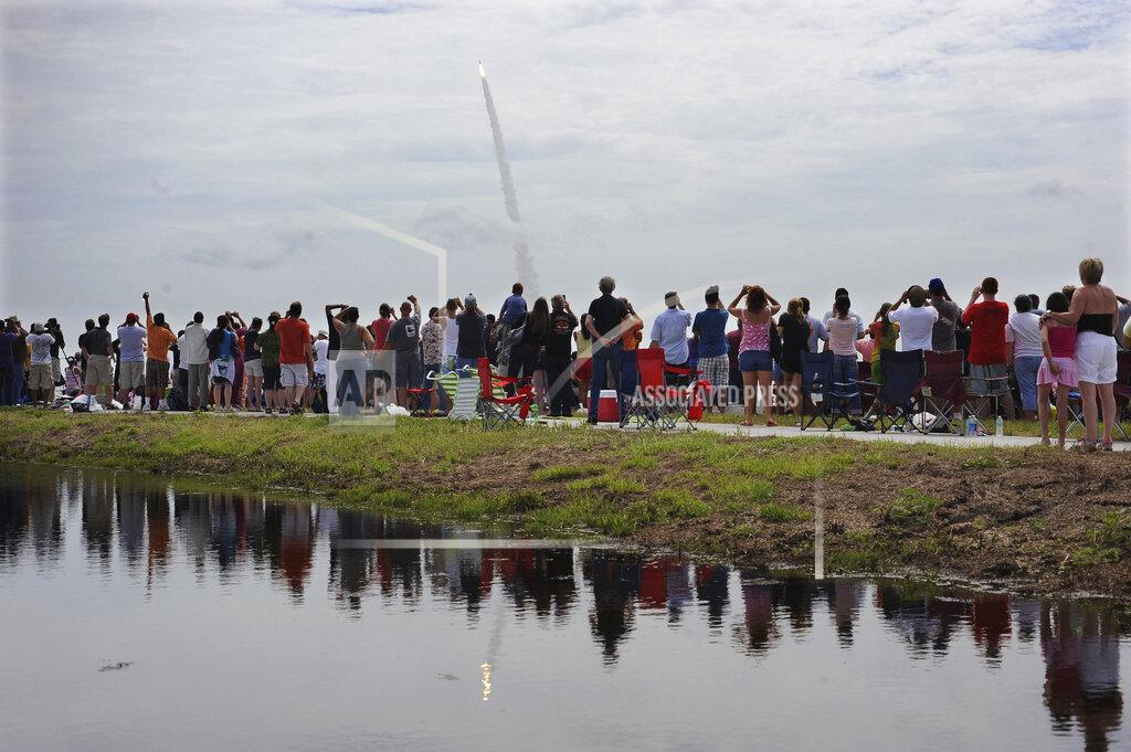 FILE - In this July 8, 2011 file photo, spectators watch the space shuttle Atlantis lift off from the Kennedy Space Center at Cape Canaveral, Fla. Atlantis was the 135th and final space shuttle launch for NASA. On Friday, May 1, 2020, NASA and SpaceX urged everyone to stay home for the first home launch of astronauts in nearly a decade, coming up later in the month, because of the coronavirus pandemic. (AP Photo/Phil Sandlin)
