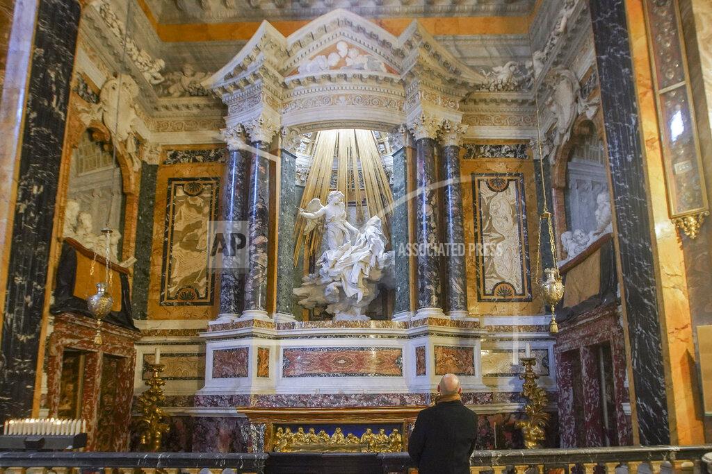 Andrew Medichini A visitor admires the marble sculptural group "Ecstasy of Saint Teresa" made between 1647 and 1652, by Baroque architect and sculptor Gian Lorenzo Bernini, in the Cornaro Chapel of Rome's Saint Mary of Victory church, Tuesday, Dec. 15, 2020. Like elsewhere in Europe, museums and art galleries in Italy were closed this fall to contain the spread of COVID-19, meaning art lovers must rely on virtual tours to catch a glimpse of the treasures held by famous institutions such as the Uffizi in Florence and the Vatican Museums in Rome. However, some exquisite gems of Italy's cultural heritage remain on display in real life inside the country's churches, some of which have collections of renaissance art and iconography that would be the envy of any museum. (AP Photo/Andrew Medichini)