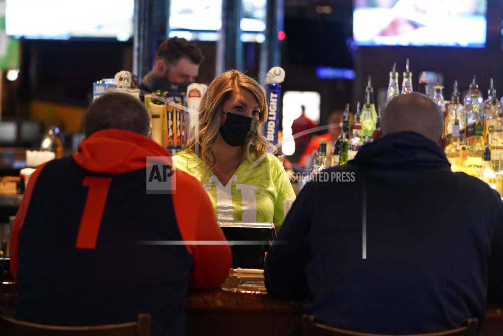 Darron Cummings Jillian Smith takes an order from people at Kilroy's Bar & Grill, Sunday, March 14, 2021, in Indianapolis. The NCAA Tournament and bars were made for each other, with fans of powerhouse teams like Gonzaga and longshots like Colgate pouring in to cheer their teams. Until last year, that is, when COVID-19 blew up everybody’s brackets. This year, the tournament’s back, and bars and restaurants, some shuttered for months, are open for March Madness, though things may look a little different. (AP Photo/Darron Cummings)