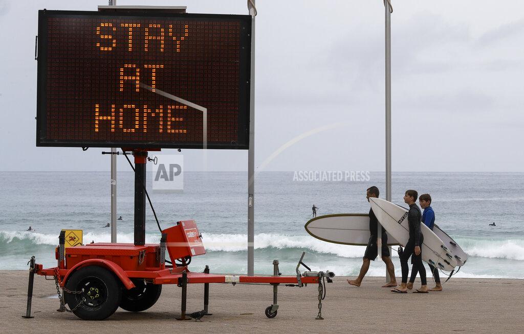Mark Baker Surfers carry their boards along the beach front at Manly on the northern beaches in Sydney, Australia, Monday, Dec. 21, 2020. Sydney's northern beaches are in a lockdown similar to the one imposed during the start of the COVID-19 pandemic in March as a cluster of cases in the area increased to more than 80. (AP Photo/Mark Baker)