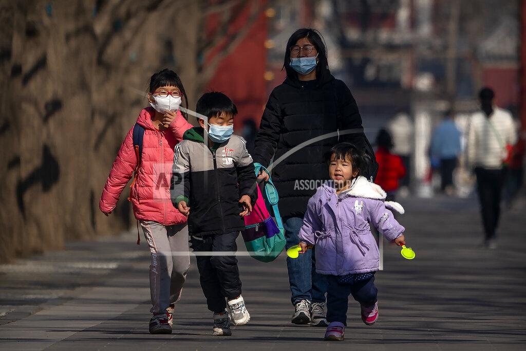 Mark Schiefelbein In this Tuesday, Feb. 9, 2021, photo, children wearing face masks run along a path at a public park in Beijing. China's population grew last year, the government said Thursday, following a report that a census might have found a surprise decline, possibly adding to downward pressure on economic growth. (AP Photo/Mark Schiefelbein)