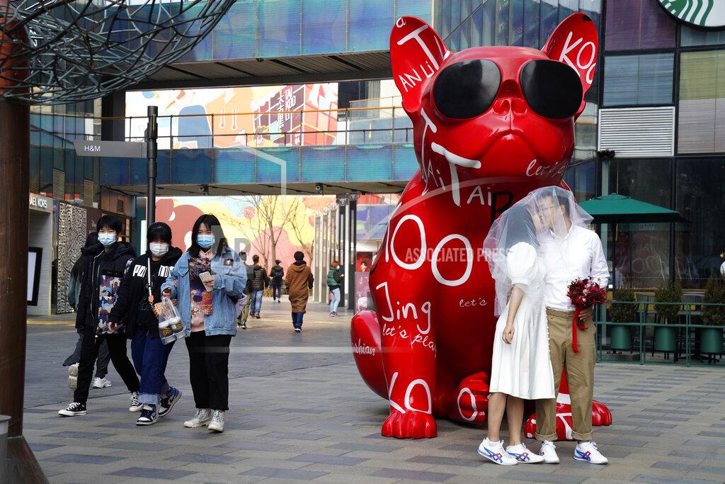 Ng Han Guan A couple poses for wedding photos in a popular shopping district in Beijing Thursday, Feb. 25, 2021. The state of the world's second largest economy takes precedence among the myriad issues presented by Chinese Premier Li Keqiang in his address at the National People's Congress opening session to take place on Friday, March 5. 2021. (AP Photo/Ng Han Guan)