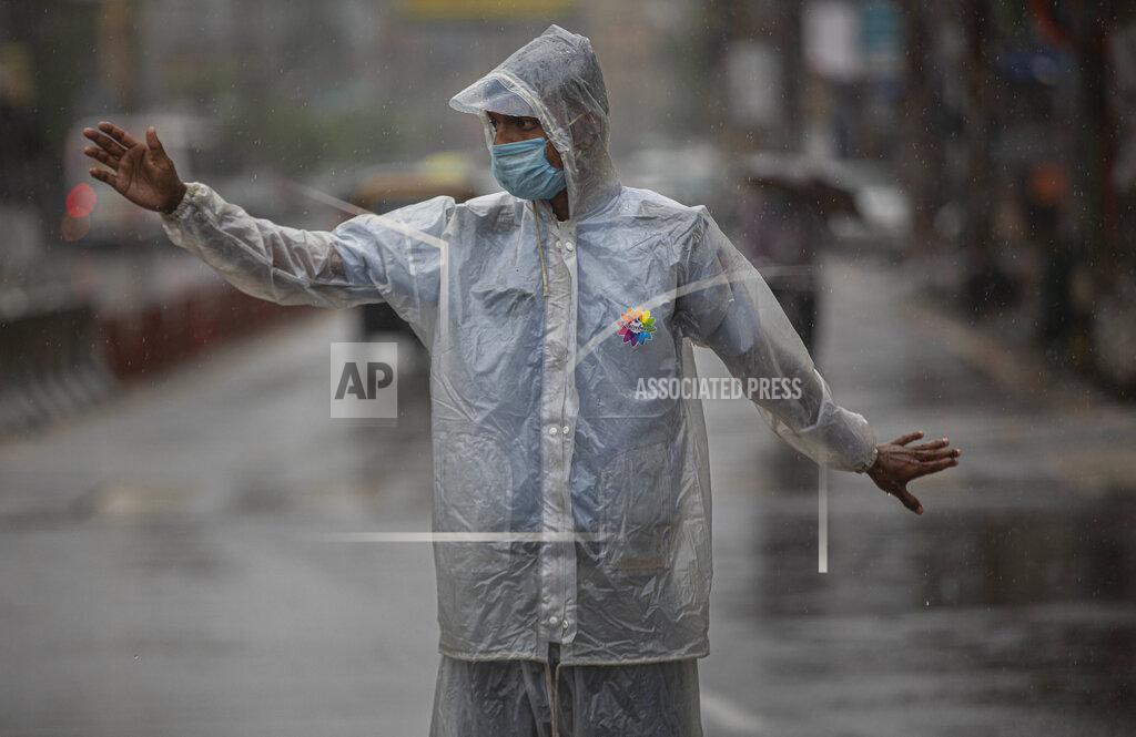 Anupam Nath An Indian traffic police person controls traffic during heavy rain in Gauhati, India, Thursday, May 21, 2020. A powerful cyclone ripped through densely populated coastal India and Bangladesh, blowing off roofs and whipping up waves that swallowed embankments and bridges and left entire villages without access to fresh water, electricity and communications. (AP Photo/Anupam Nath)