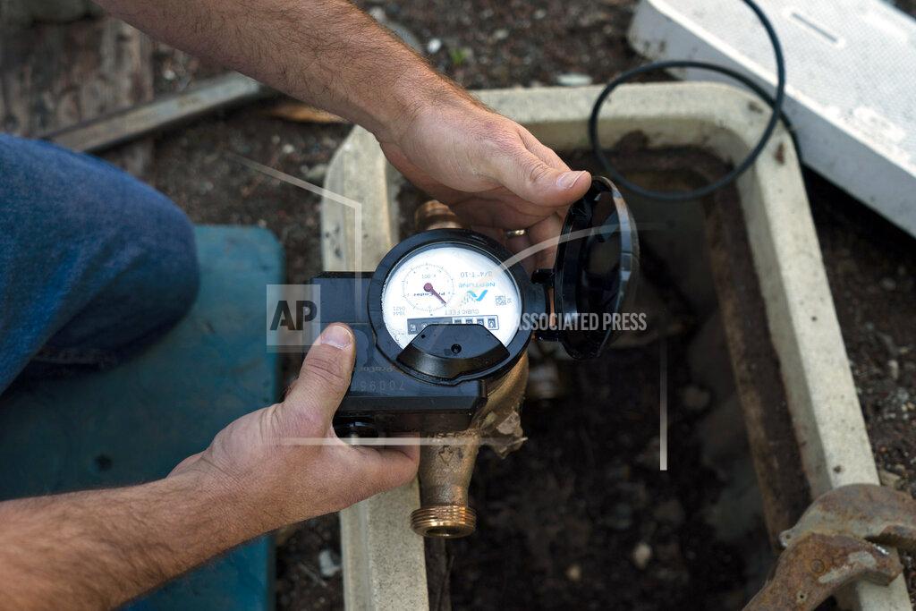 Jae C. Hong FILE - Cason Gilmer, a senior field customer service representative from the Las Virgenes Municipal Water District, installs an advanced water metering system in Agoura Hills, Calif., Jan. 5, 2022. The sight of fountains, swimming pools, gardens and golf courses in Western cities like Phoenix, Los Angeles, Las Vegas, San Diego and Albuquerque can seem jarring with drought and climate change tightening their grip on the region. But Western water experts say they aren’t necessarily cause for concern. Many Western cities over the past three decades have diversified their water sources, boosted local supplies, and use water more efficiently now than in the past. (AP Photo/Jae C. Hong, File)