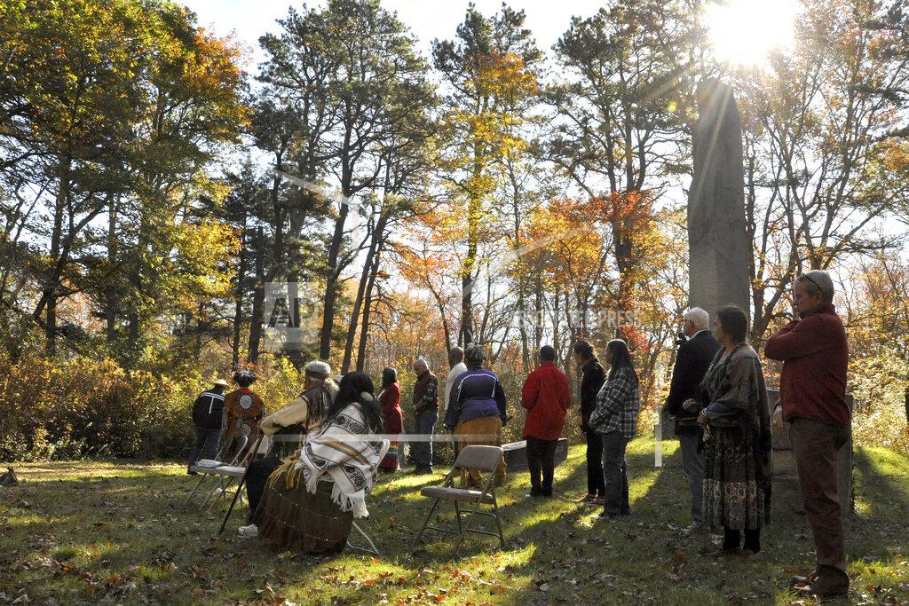 Alex Nunes Members of the Narragansett Indian Tribe and others gather, Saturday, Oct. 23, 2021, in a wooded area, in South Kingstown, R.I., at what is believed to be the site of the Great Swamp Massacre, The Public's Radio reported. The land where the Rhode Island Narragansett tribe survived near-annihilation in a battle with English colonists on Dec. 19, 1675, has been transferred to the tribe. The transfer of the land from the Rhode Island Historical Society was finalized Friday, Oct. 22. (Alex Nunes/The Public's Radio, WNPN 89.3FM via AP)