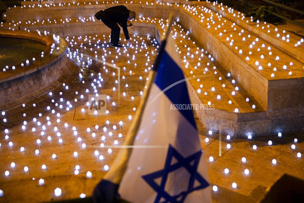 Oded Balilty A man turns on LED candles at a memorial for Israel's victims of COVID-19, in Jerusalem, Sunday, Nov. 8, 2020. (AP Photo/Oded Balilty)