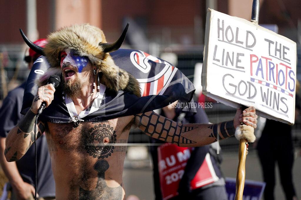 Jake Angeli, a supporter of President Donald Trump, speaks at a rally outside the Maricopa County Recorder's Office Saturday, Nov. 7, 2020, in Phoenix. Democrat Joe Biden defeated President Donald Trump to become the 46th president of the United States on Saturday, positioning himself to lead a nation gripped by the historic pandemic and a confluence of economic and social turmoil. (AP Photo/Ross D. Franklin)