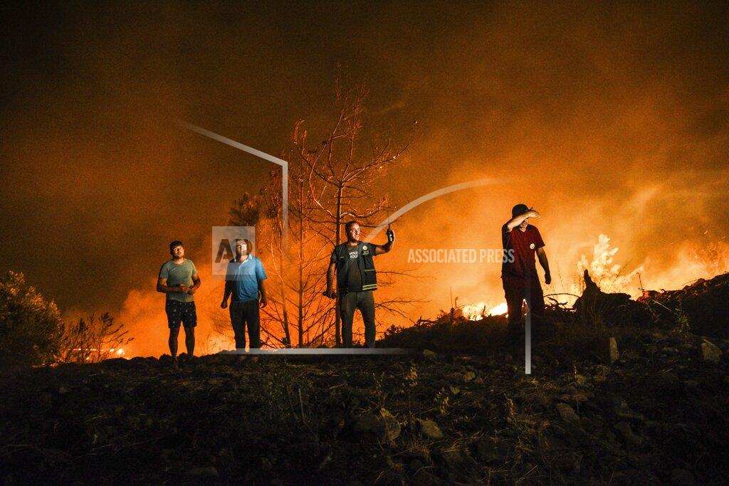 Uncredited Firefighters and local villagers respond to a fire in Kirli village near the town of Manavgat, in Antalya province, Turkey, early Friday July 30, 2021. The fire that continued all night could not be brought under control and people living in the village started to evacuate. Wildfires are common in Turkey's Mediterranean and Aegean regions during the arid summer months, although some previous forest fires have been blamed on arson. (AP Photo)