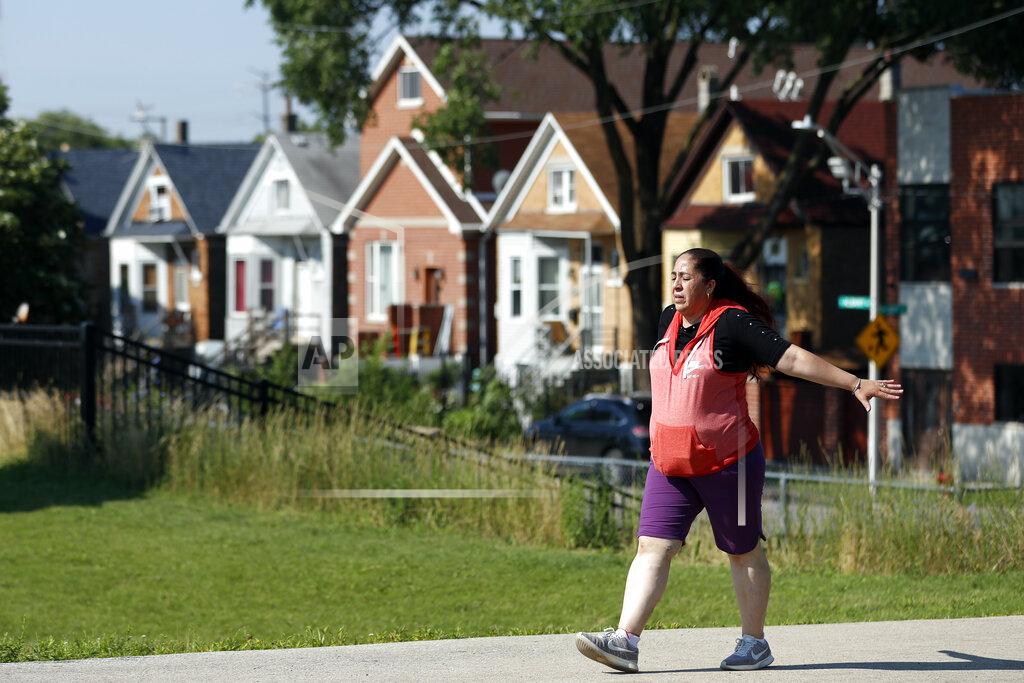 Shafkat Anowar Eugenia Rodriguez walks in Chicago's La Villita Park, Thursday, July 1, 2021. She is required to get out for a walk or a run every morning to keep her varicose veins active and hasn't been eligible for insurance coverage after overstaying a visitor visa from Mexico. Rodriguez used to wake up every two or three hours at night to check on her mother in their Chicago home. Since getting insurance through the Illinois program, her mother has proper medications. (AP Photo/Shafkat Anowar)
