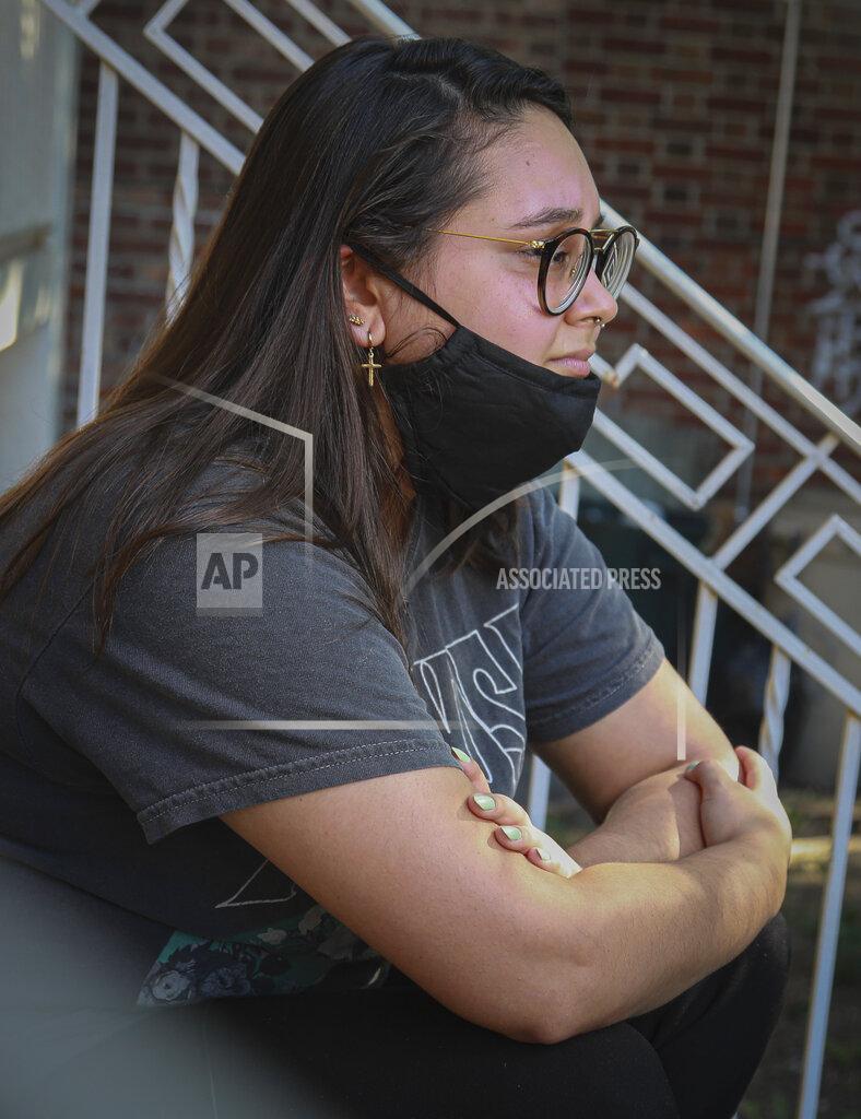 Bebeto Matthews Natalia Afonso, 27, an international student from Brazil at Brooklyn College, sits on a stoop outside her home during an interview, Thursday, July 9, 2020, in New York. Afonso, who is studying teaching education and finished her first semester this spring, said she has lived in the U.S. for 7 years and "I don't see myself moving back to Brazil at this point. (AP Photo/Bebeto Matthews)