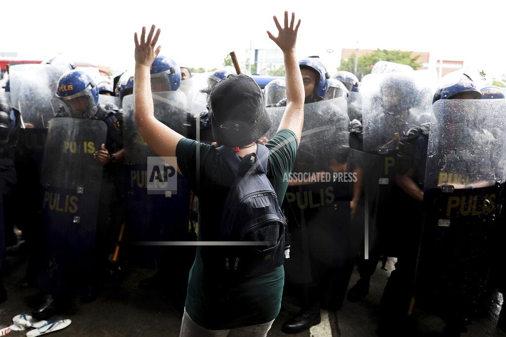 Basilio Sepe An activist raises her hands as police disperse their group during a rally against presidential frontrunner Ferdinand "Bongbong" Marcos and running mate Sara Duterte, daughter of the current president, during a rally at the Commission on Human Rights in Quezon City, Metro Manila, Philippines on Wednesday. May 25, 2022. Marcos Jr. continues to lead in the official canvassing of votes. (AP Photo/Basilio Sepe)