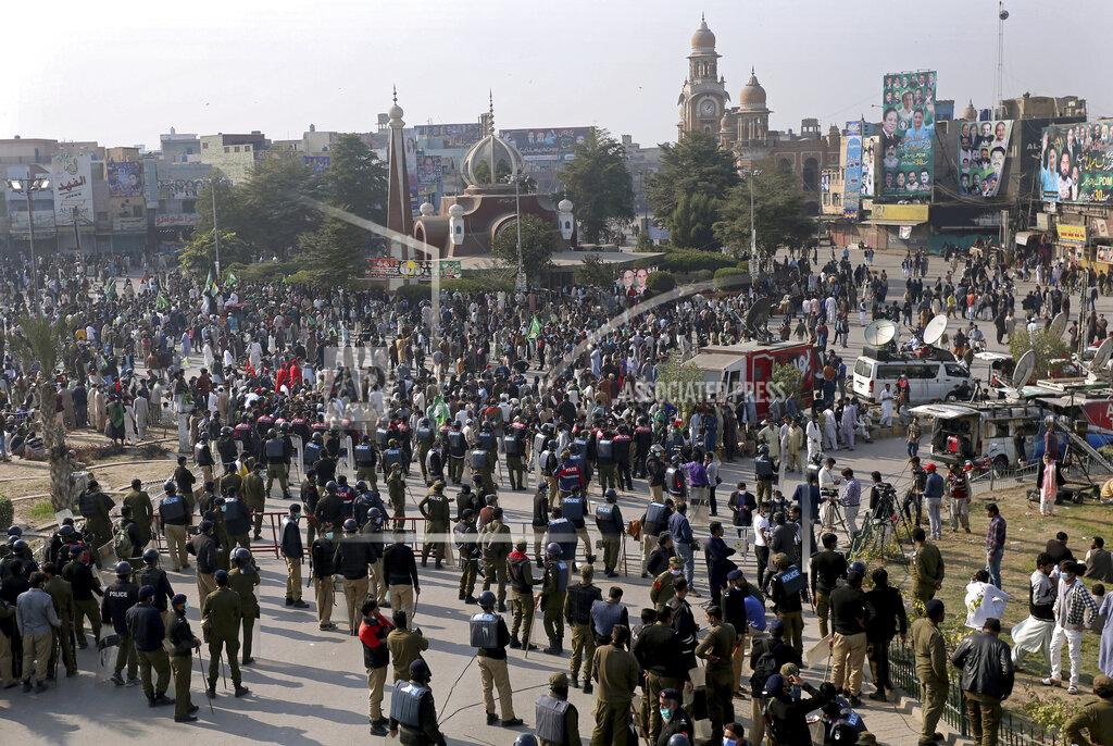 Asim Tanveer Pakistani police officers stand guard while supporters of the Pakistan Democratic Movement, an alliance of opposition parties, gather at a main intersection before an anti-government rally, in Multan, Pakistan, Monday, Nov. 30, 2020. Pakistani police arrested hundreds of supporters of opposition parties ahead of a planned rally Monday calling for the country's prime minister to resign, a move the government defended as necessary to combat the coronavirus pandemic. (AP Photo/Asim Tanveer)