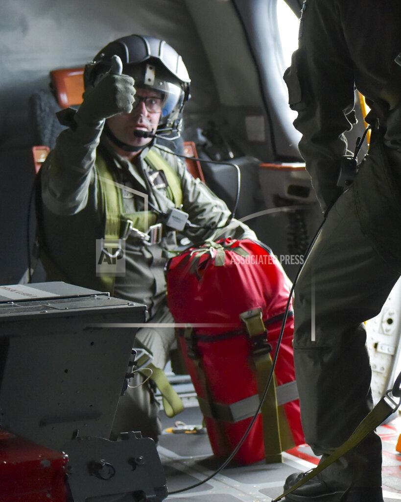 Uncredited In this image supplied by the Royal New Zealand Air Force (RNZAF), a crew member of a RNZAF Orion gestures before dropping a survival pack to a boat near Makin Island in Kiribati, Monday, May 23, 2022. New Zealand's military said Tuesday that an air force plane found seven people who had gone missing. They were aboard two small boats near the remote Pacific nation of Kiribati. (RNZAF via AP)
