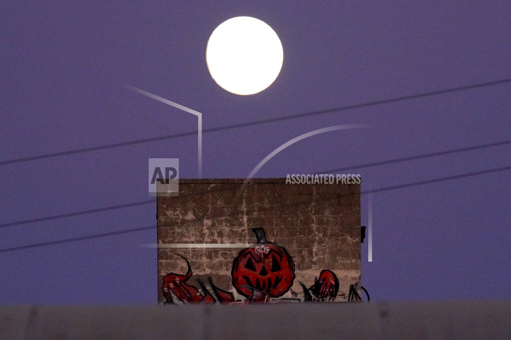 Charlie Riedel The nearly full moon rises beyond Halloween artwork painted on a building Thursday, Oct. 29, 2020, in Kansas City, Mo. (AP Photo/Charlie Riedel)