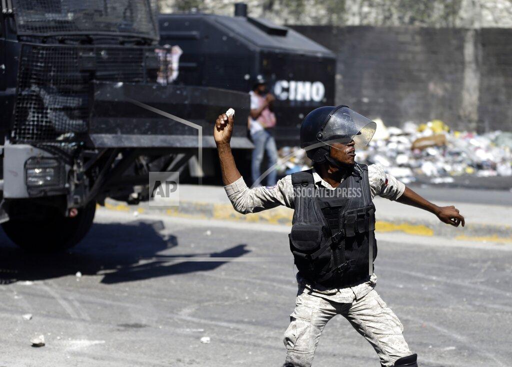 Dieu Nalio Chery A police officer throws a stone at protesters during a protest to demand the resignation of Haiti's president Jovenel Moise in Port-au-Prince, Haiti, Wednesday, Jan. 20, 2021. Moise has one more year in power, but a growing groundswell of opposition is organizing protests and demanding he resign next month amid spiraling crime and a crumbling economy. ( AP Photo/ Dieu Nalio Chery)