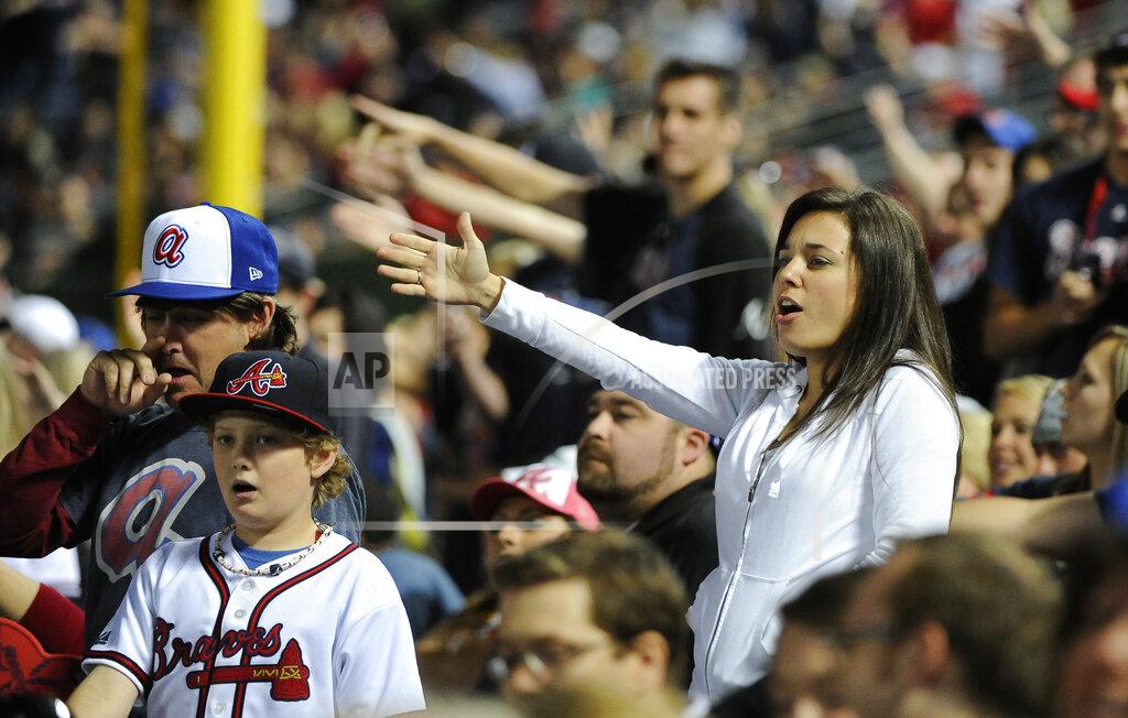 FILE - In this May 2, 2014, file photo, Atlanta Braves fans do the tomahawk chop during the ninth inning of a baseball game with the San Francisco Giants, in Atlanta. The Atlanta Braves say they have no plans to follow the lead of the NFL's Washington Redskins and change their team name. The team said in a letter to season ticket holders they are examining the fan experience, including the tomahawk chop chant, and have formed a "cultural working relationship" with the Eastern Band of the Cherokees in North Carolina. (AP Photo/David Tulis, File)