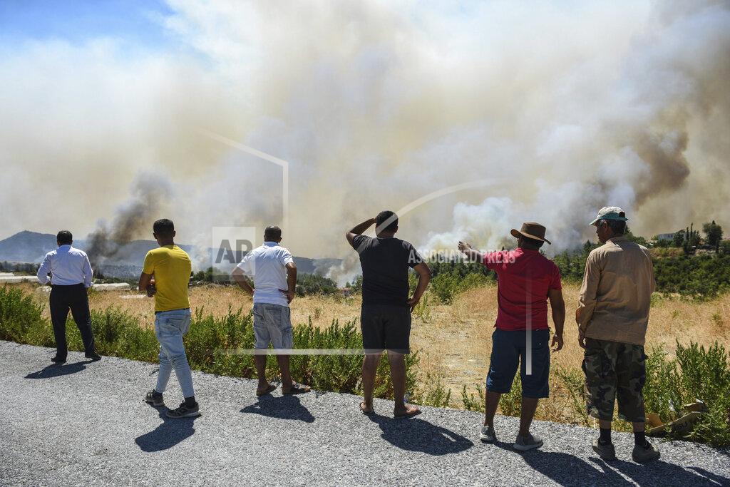 Uncredited People watch wildfires in Kacarlar village near the Mediterranean coastal town of Manavgat, Antalya, Turkey, Saturday, July 31, 2021. The death toll from wildfires raging in Turkey's Mediterranean towns rose to six Saturday after two forest workers were killed, the country's health minister said. Fires across Turkey since Wednesday burned down forests, encroaching on villages and tourist destinations and forcing people to evacuate. (AP Photo)